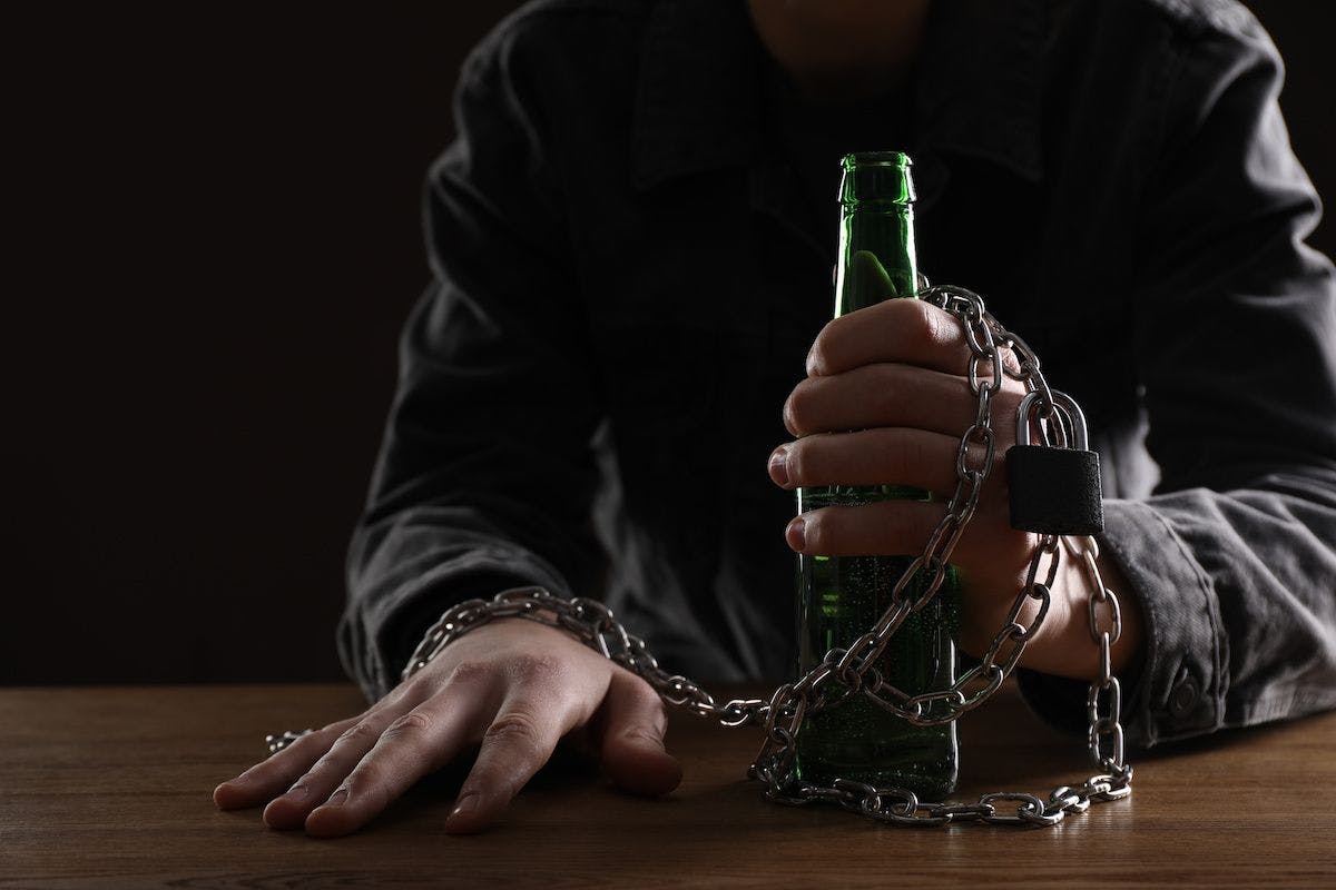 aud alcohol use disorder man chained to bottle: © New Africa - stock.adobe.com