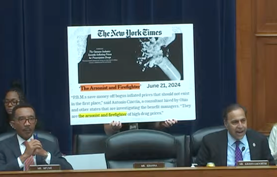 Rep. Raja Krishnamoorthi (D-Illinois) speaks as an aide holds a copy of a New York Times citation about pharmacy benefit managers during a hearing of the House Committee on Oversight and Accountability on July 23, 2024.